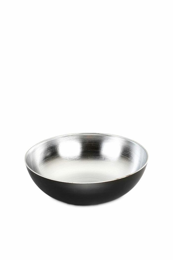 Eine schlichte, runde Metallschale mit einem glänzenden silbernen Innenraum und einem mattschwarzen Außenbereich. Die Schale hat einen breiten Rand und eine flache Form, und sie steht auf einer neutralen weißen Fläche ohne weitere Dekorationen.