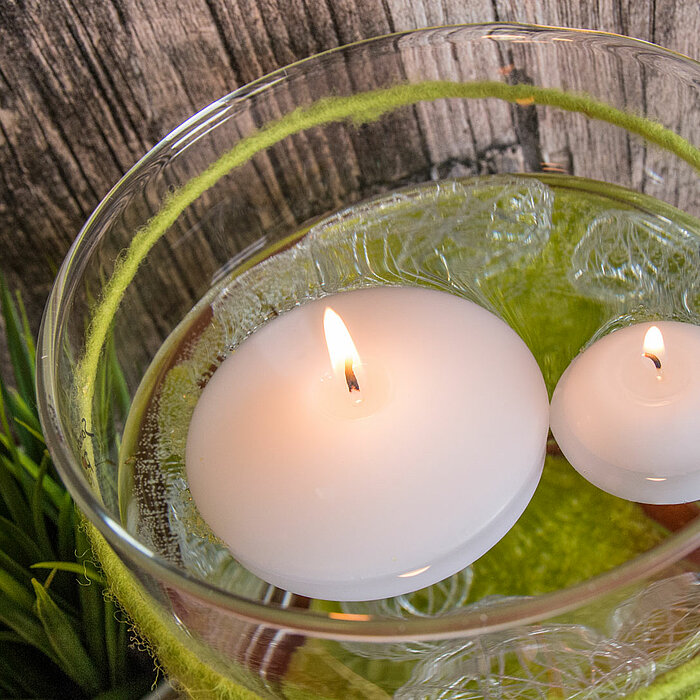 Eine liegende, rosafarbene Schwimmkerze vom Hersteller "Wenzel" mit einer eleganten, glatten Oberfläche. Die Kerze hat eine flache, runde Form und der Docht ist mittig platziert.