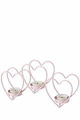 Drei Herz-Kerzenhalter aus rosa Metall, die jeweils ein brennendes Teelicht tragen. Die Kerzenhalter haben unterschiedliche Größen und sind harmonisch nebeneinander angeordnet. Die Anordnung strahlt eine romantische und gemütliche Atmosphäre aus.