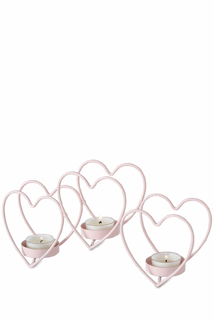 Drei Herz-Kerzenhalter aus rosa Metall, die jeweils ein brennendes Teelicht tragen. Die Kerzenhalter haben unterschiedliche Größen und sind harmonisch nebeneinander angeordnet. Die Anordnung strahlt eine romantische und gemütliche Atmosphäre aus.