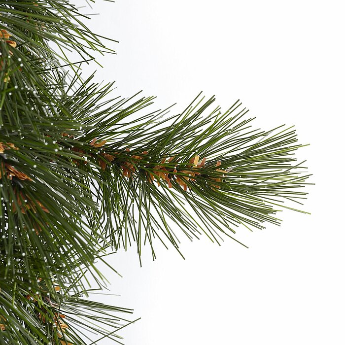 Ein dichter Ast eines künstlichen Tannenbaums mit feinen grünen Nadeln, die sich detailliert und realistisch vom weißen Hintergrund abheben. Einige der Nadeln haben kleine braune Akzente, die dem Ast ein natürliches Aussehen verleihen.