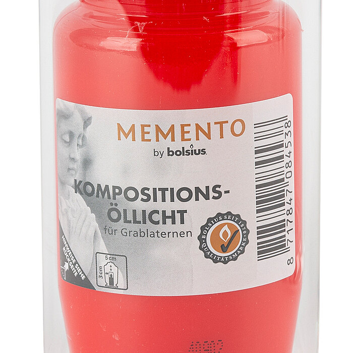 Eine rote Kompositions-Öllampe der Marke "Memento by Bolsius" ist in einem durchsichtigen Glasbehälter zu sehen. Auf dem Etikett steht "KOMPOSITIONS-ÖLLICHT für Grablaternen". Das Etikett zeigt zusätzlich ein Bild einer betenden Person neben weiteren Prod