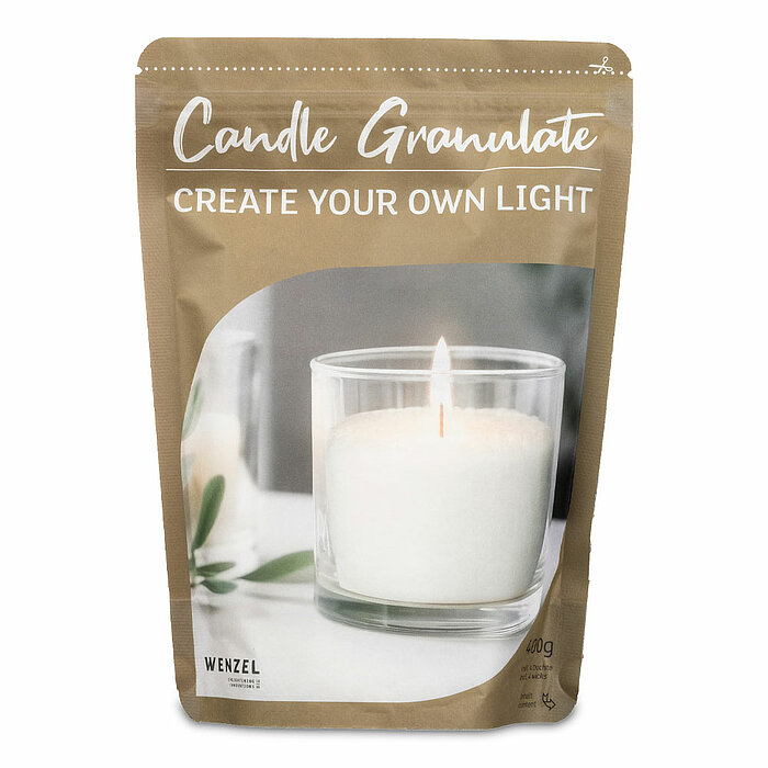 Eine Verpackung mit der Aufschrift "Candle Granulate - Create Your Own Light" und "Wenzel" ist zu sehen. Auf der Verpackung ist ein Bild eines gläsernen Kerzenhalters mit einer brennenden weißen Kerze abgebildet. Die Verpackung hat eine beige Farbe und ze