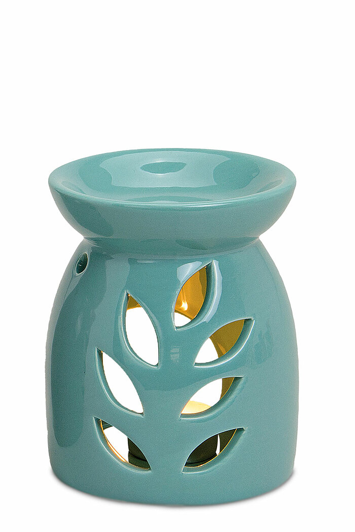 Eine türkisfarbene Keramik-Duftlampe mit einem eleganten Blätterausschnitt-Design. Die Lampe hat eine runde, flache Schale oben und ist hohl, damit ein Teelicht hineingestellt werden kann. Das Licht des Teelichts scheint durch die ausgestanzten Blattmuste