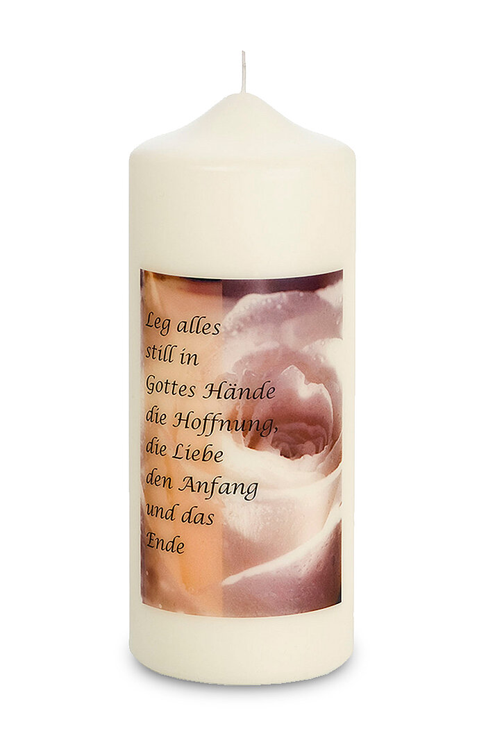 Eine weiße Stumpenkerze mit einer Aufschrift. Auf der Kerze ist ein Bild von einer Rose, darüber steht ein Zitat: "Leg alles still in Gottes Hände, die Hoffnung, die Liebe, den Anfang und das Ende".