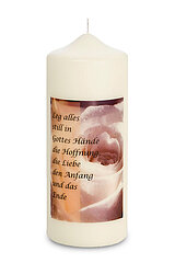 Eine weiße Stumpenkerze mit einer Aufschrift. Auf der Kerze ist ein Bild von einer Rose, darüber steht ein Zitat: "Leg alles still in Gottes Hände, die Hoffnung, die Liebe, den Anfang und das Ende".