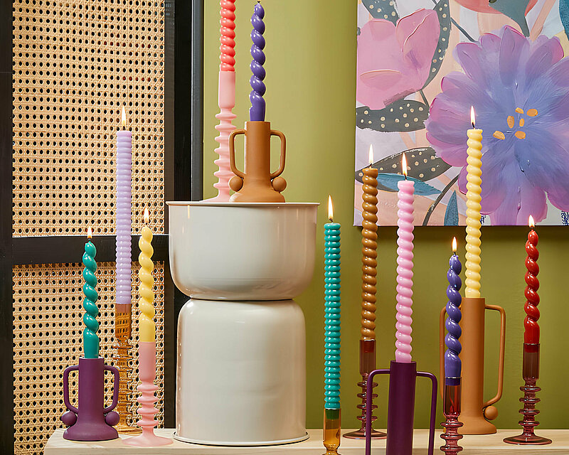 Ein bunter Raum mit vielen verschiedenen Tafelkerzen in bunten Farben. Die Kerzen wurden aus gedrehtem Wachs geformt und sehen wie Spiralen aus.