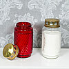 Eine rote und eine weiße Grabkerze von Bolsius stehen nebeneinander auf einer weißen Oberfläche. Beide Kerzen sind in geriffelten Glasbehältern mit goldenen Deckeln, wobei der Deckel der roten Kerze abgenommen ist und daneben liegt. Der Hintergrund ist ei