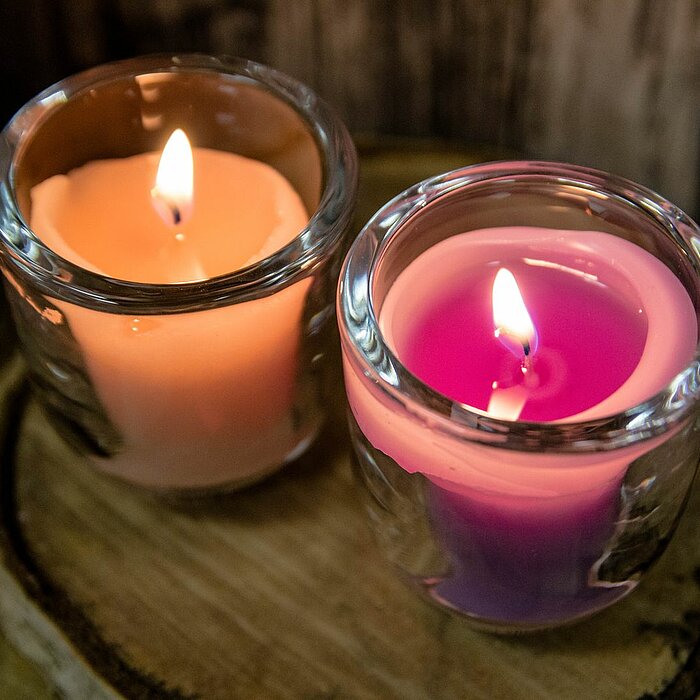 Einige dunkelviolette Lavendelblüten liegen verstreut auf einer hellen, strukturierten Oberfläche. Die zarten Blüten und langstieligen Blätter schaffen eine ruhige und angenehme Atmosphäre.