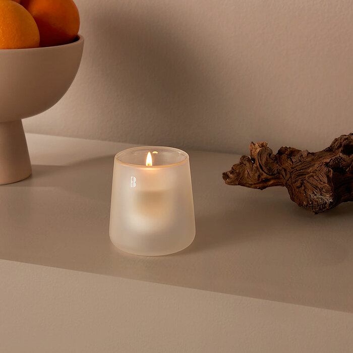 Ein minimalistischer Schreibtisch mit einer Holzplatte und einem schwarzen Metallgestell. Darauf befinden sich ein geschlossenes silbernes Laptop, ein schwarzer Stift mit einem Notizbuch, eine weiße Tasse, ein Penhalter mit Stiften, ein geschlossenes Buch