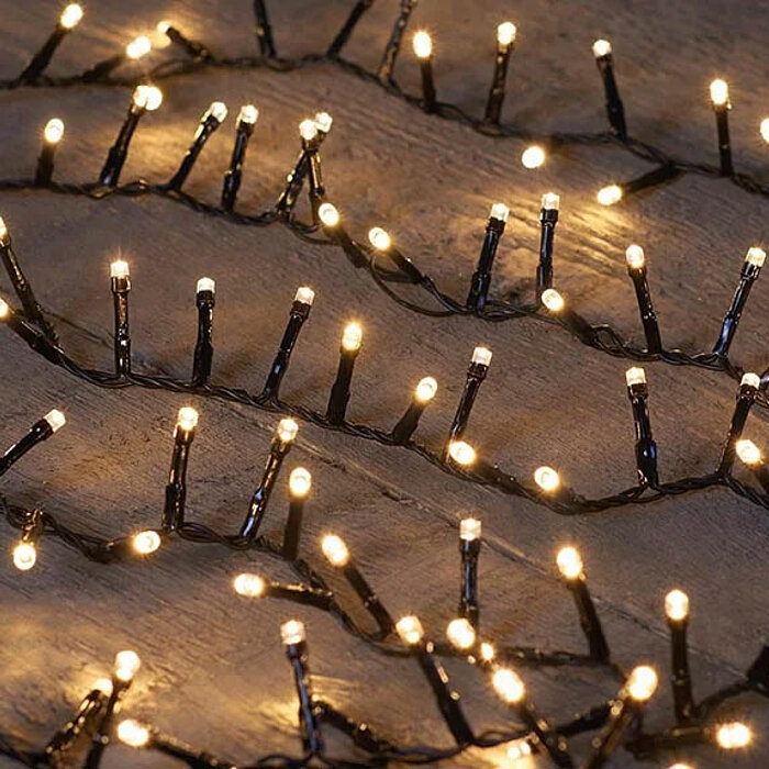 Das Bild zeigt einen festlich geschmückten Weihnachtsbaum mit zahlreichen roten und silbernen Kugelornamenten. Der Baum ist üppig beleuchtet mit warmweißen Lichterketten, die ein gemütliches und festliches Ambiente erzeugen. Die Lichter und glänzenden Kug