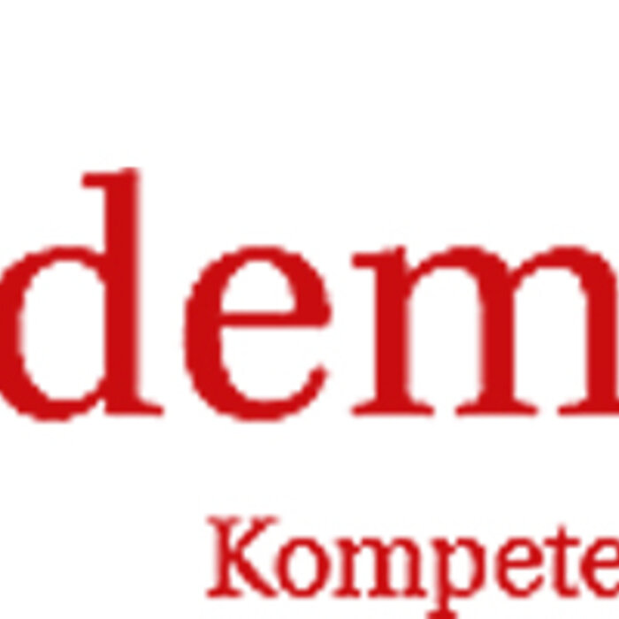 Drei brennende Wiedemann Kerzen, zwei Stumpen in verschiedenen Größen und eine Kugelkerze, in den Farben Weiß und Silber, stehen auf einem weißen Tisch. Die Kerzen sind elegant auf einem silbernen Tablett arrangiert, umgeben von weißen und silbernen Dekor