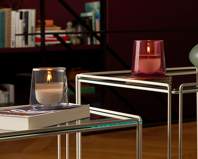 Zwei brennende Clean-Light Kerzengläser in dunklem Pink und in zartem Grau. Die Kerzengläser sind durchsichtig und mit aromatischen Duft-Nachfüllkerzen befüllt.