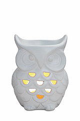 Ein weißer, eulenförmiger Teelichthalter aus Keramik. Die Eule hat große, runde Augen und ein detailliert ausgearbeitetes Federkleid, in dem mehrere herzförmige Löcher eingelassen sind. Durch diese Löcher scheint diffuses, warmes Licht, was dem Objekt ein