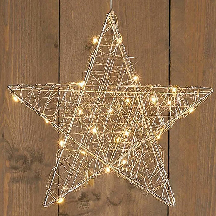 Ein stilvoller, beleuchteter Stern aus Draht hängt vor einer Holzwand. Die kleinen, warmweißen Lichter umhüllen den Stern und erzeugen eine gemütliche und festliche Atmosphäre. Die Holzwand im Hintergrund verleiht dem Bild eine rustikale und einladende No