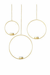 Drei runde, goldene Hängelaternen von Boltze, die in verschiedenen Höhen an schmalen Ketten aufgehängt sind. Jede Laterne hat im unteren Teil eine kleine, weiße Kerze in einem goldenen Kerzenhalter. Der Hintergrund ist einfarbig weiß, was die minimalistis