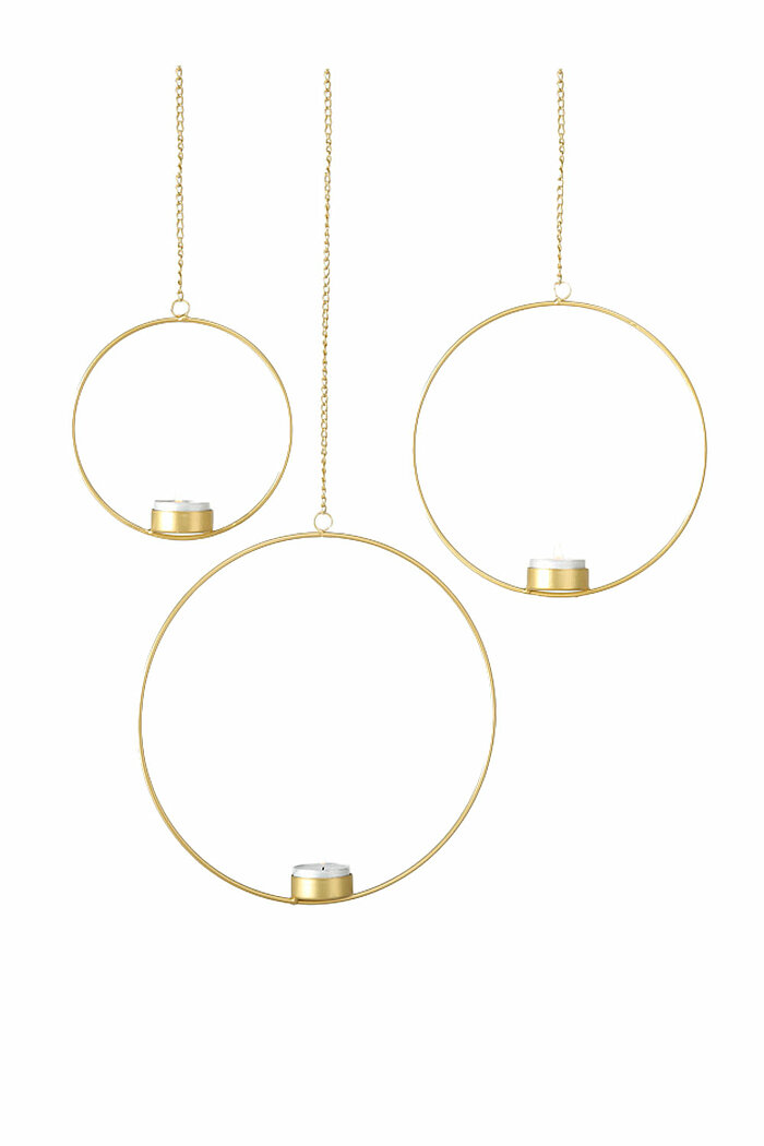 Drei runde, goldene Hängelaternen von Boltze, die in verschiedenen Höhen an schmalen Ketten aufgehängt sind. Jede Laterne hat im unteren Teil eine kleine, weiße Kerze in einem goldenen Kerzenhalter. Der Hintergrund ist einfarbig weiß, was die minimalistis