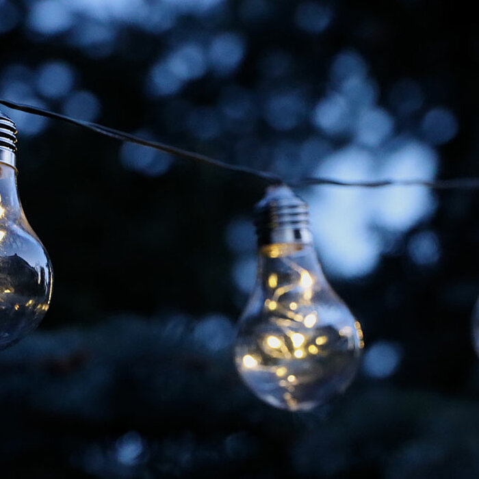 Ein schwarzes, rechteckiges Solarpanel auf einem stabilen Pfosten mit Spitzende. Das Solarpanel enthält mehrere parallele Streifen, die die Solarzellen darstellen. Das Spitzende ermöglicht das Einstecken in den Boden für eine stabile Platzierung im Freien
