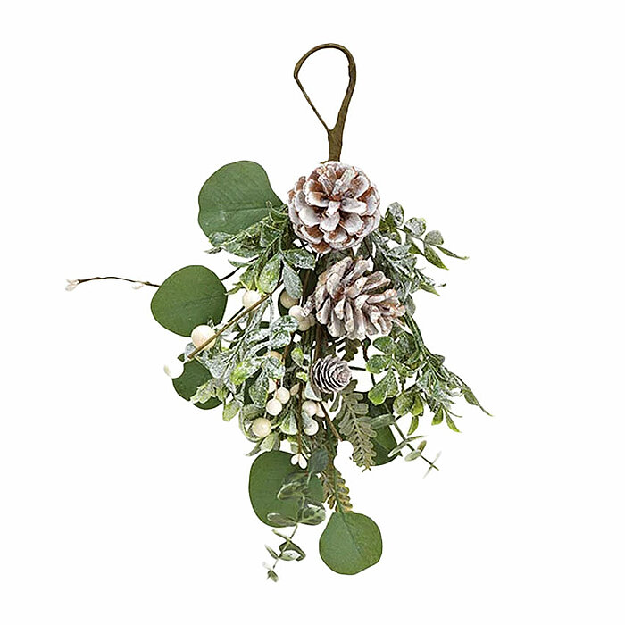 Ein winterliches Arrangement: Zwei beschneite Kiefernzapfen hängen an einer Schlaufe aus braunem Band. Umrahmt werden sie von grünen Eukalyptusblättern und kleinen, weißen Beeren. Die Mischung aus natürlichen und kunstvollen Elementen strahlt eine festlic