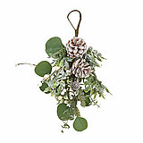 Ein winterliches Arrangement: Zwei beschneite Kiefernzapfen hängen an einer Schlaufe aus braunem Band. Umrahmt werden sie von grünen Eukalyptusblättern und kleinen, weißen Beeren. Die Mischung aus natürlichen und kunstvollen Elementen strahlt eine festlic