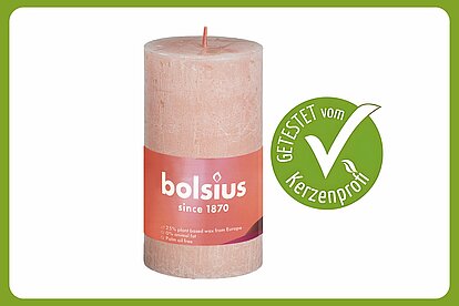 Auf dem Bild ist eine einzelne Bolsius Rustik Stumpenkerze zu sehen mit der Größe 130/68 mm. Daneben ist ein grüner Kerzenprofi getestet Button. Der Rest des Bildes ist in weiss.