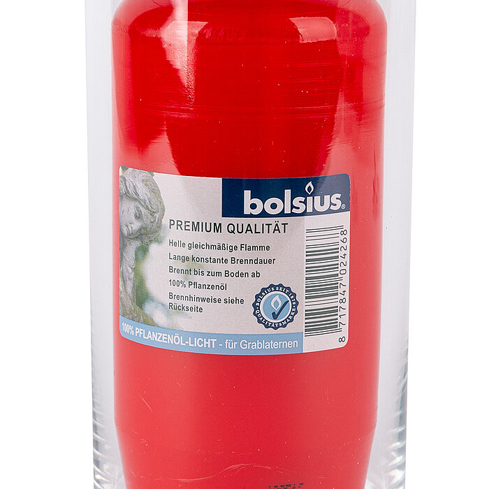 Eine große rote Grabkerze der Marke Bolsius befindet sich in einem durchsichtigen Glasbehälter. Das Etikett auf der Kerze gibt Informationen zur Premium-Qualität, wie eine helle, gleichmäßige Flamme und eine lange konstante Brenndauer. Die Kerze ist aus 1