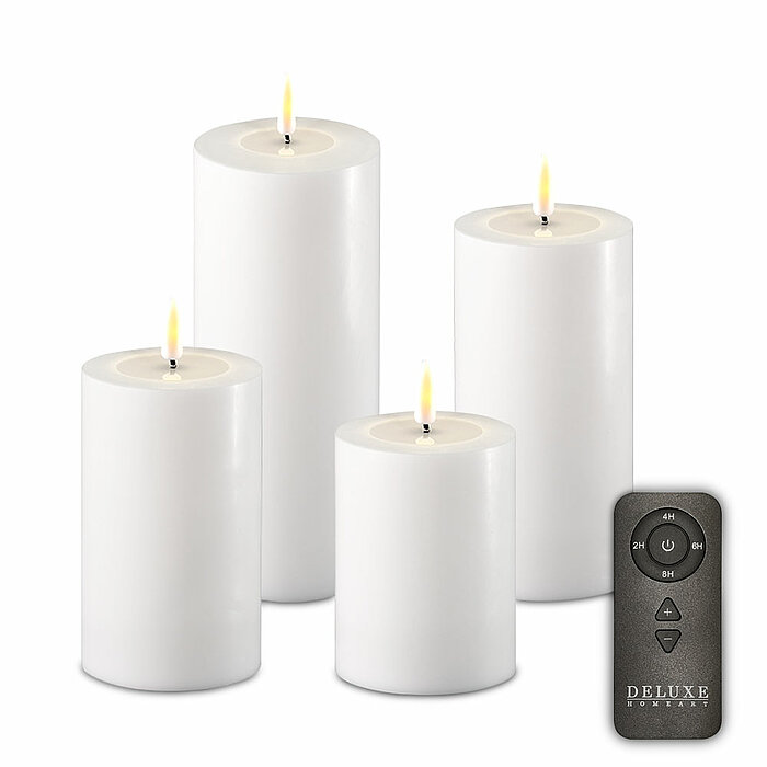 Vier brennende weiße LED-Stumpenkerzen in verschiedenen Größen, die in einer Gruppe angeordnet sind. Neben den Kerzen liegt eine schwarze Fernbedienung mit mehreren Tasten, die zur Steuerung der Kerzen dient. Die Kerzenflammen wirken realistisch und verbr