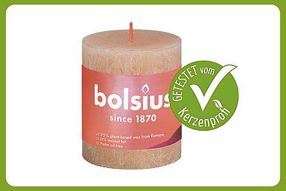 Auf dem Bild ist eine Bolsius Rustik Shine Stumpenkerze zu sehen mit der Größe 80/68 mm. Daneben ist ein grüner Kerzenprofi getestet Button. Der Rest des Bildes ist in weiss.