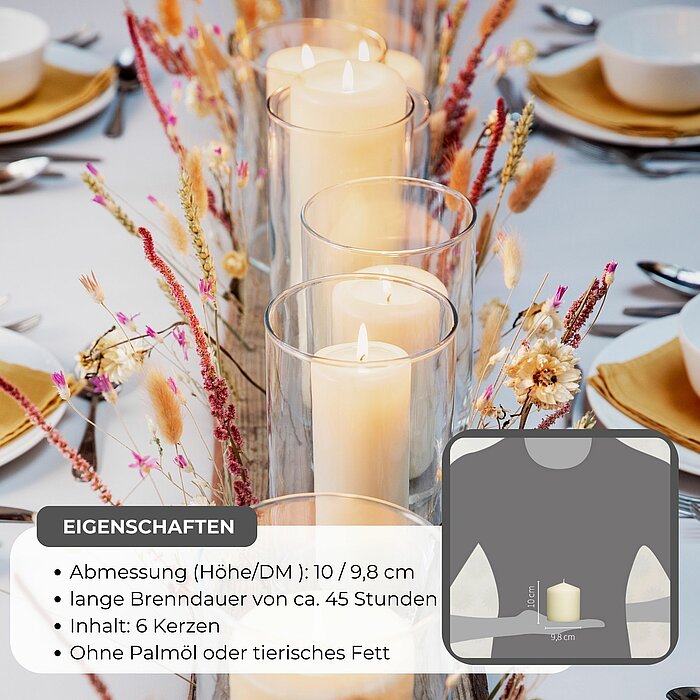 Vier brennende Stumpenkerzen in Weiß und Creme stehen zusammen auf einem runden Holztablett. Neben den Kerzen ist eine kleine Pflanze in einem Dekotopf platziert. Das Arrangement befindet sich auf einem Tisch, der mit einer zarten, beigen Spitzenborte dek