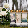 Vier Grabkerzen von Bolsius mit goldenen Deckeln stehen nebeneinander auf einem Stein. Jede Kerze ist mit einem anderen Bild verziert: eine betende Person, eine weiße Blume, fliegende Vögel und eine Pusteblume. Links neben den Kerzen liegt ein Strauß weiß